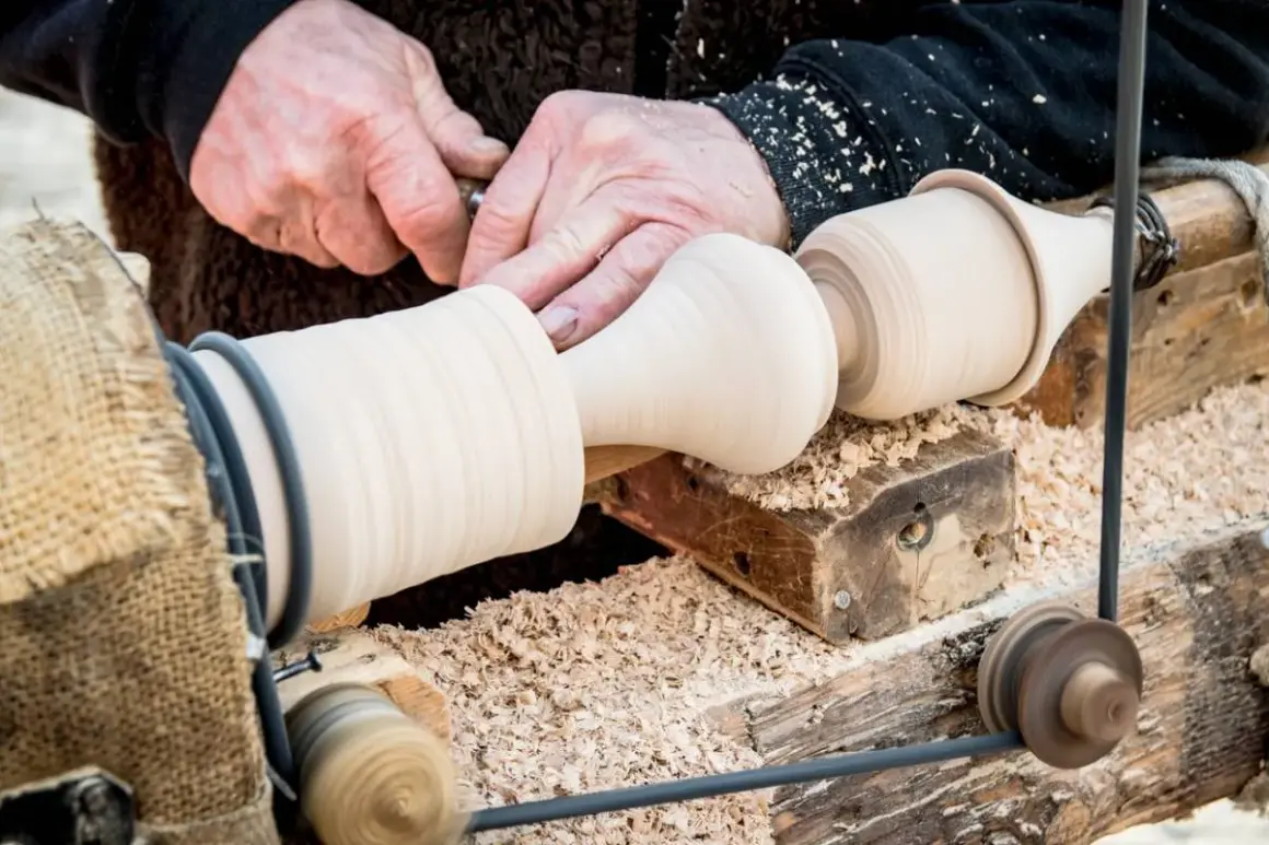 Artisan façonnant du bois sur un tour. Un exemple de ce que faire avec un tour à bois : créer des pièces uniques et élégantes.