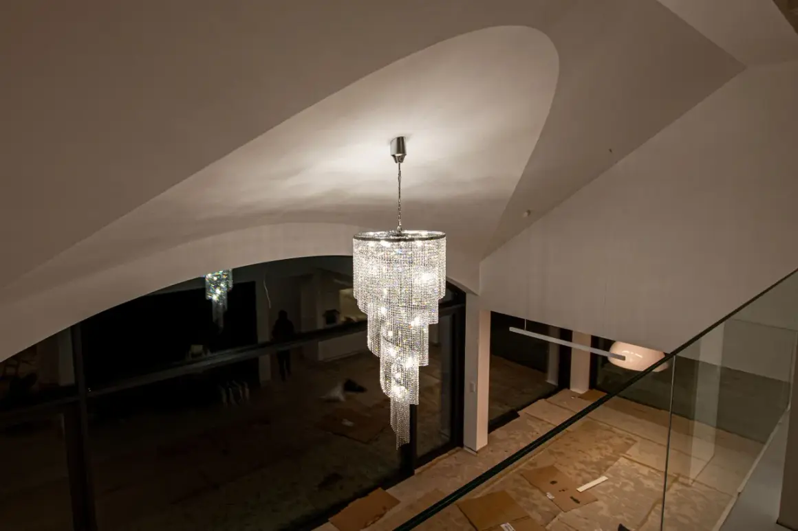 Elegancki zwis do lampy z kryształkami lśni w nowoczesnym wnętrzu z wysokim sufitem.