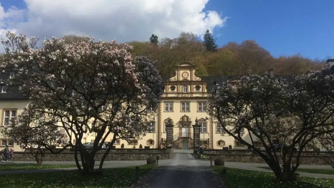 Prachtvolles Schloss Engelskirchen im Frühling, umrahmt von blühenden Magnolienbäumen.