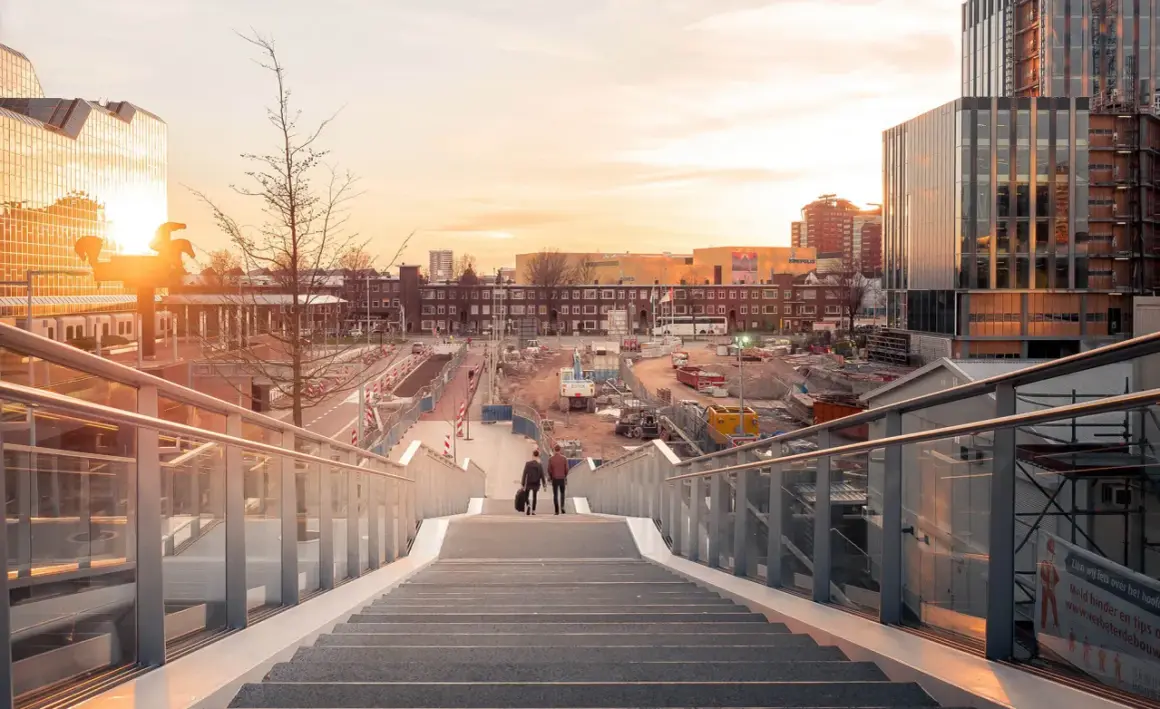 Twee mannen lopen een trap af in Utrecht, met op de achtergrond een bouwterrein en moderne gebouwen. Mooie foto locaties Utrecht.