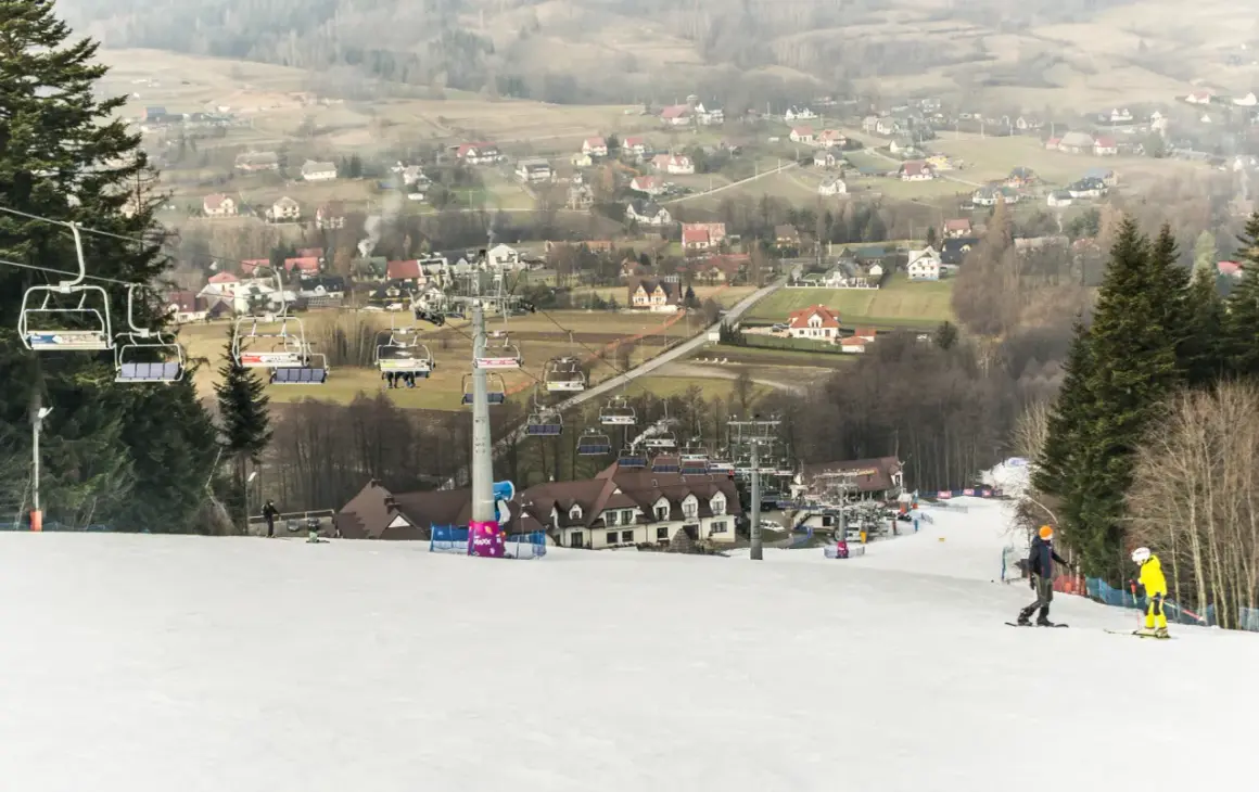 Hotel ze stokiem narciarskim dla dzieci. Kolejka krzesełkowa wwozi narciarzy na szczyt, skąd zjeżdżają po ośnieżonym stoku.