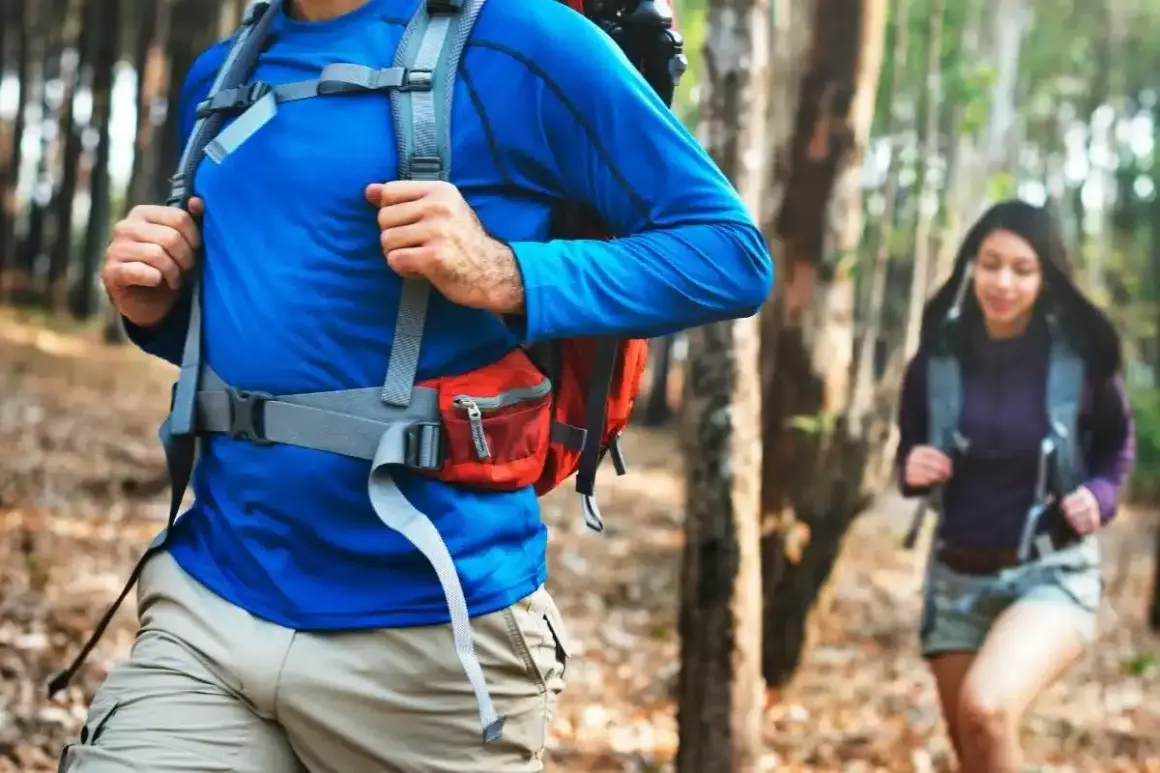 Un hombre y una mujer caminan por un sendero boscoso, ambos con una mochila mountain lista para la aventura.