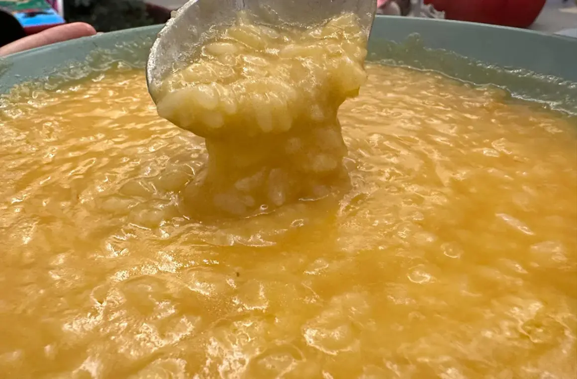 Un mestolo solleva una porzione cremosa di riso e patate, un piatto confortante e dorato.