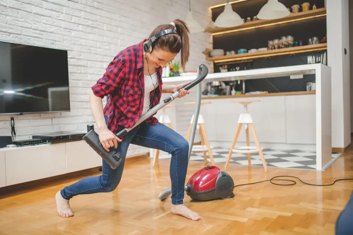 Frau mit Kopfhörern spielt Staubsauger-Gitarre. So macht **family fitness** Spaß!