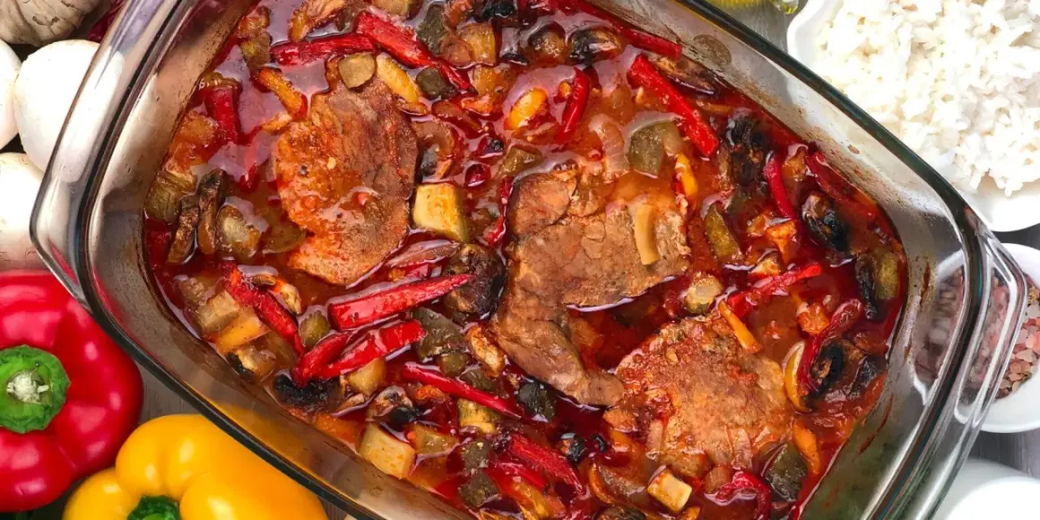 Karkówka po zbójnicku w plastrach, duszona z papryką, pieczarkami i cebulą w aromatycznym sosie. Obok miseczka ryżu.