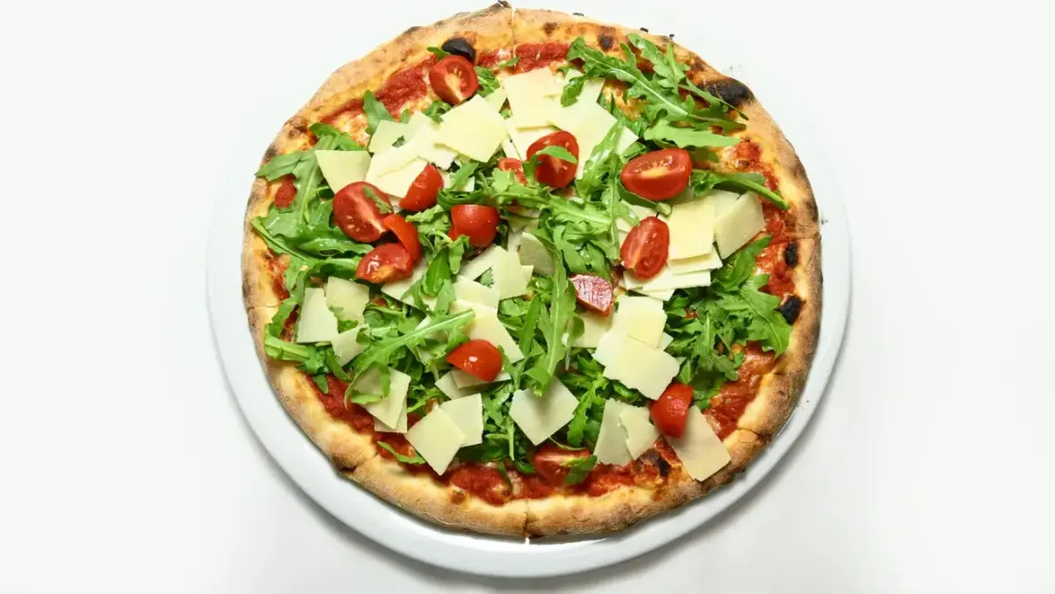 Pizza z rukolą i pomidorkami, z płatkami parmezanu. Świetna opcja, co zamiast sera na pizzy, gdy chcesz czegoś lżejszego.