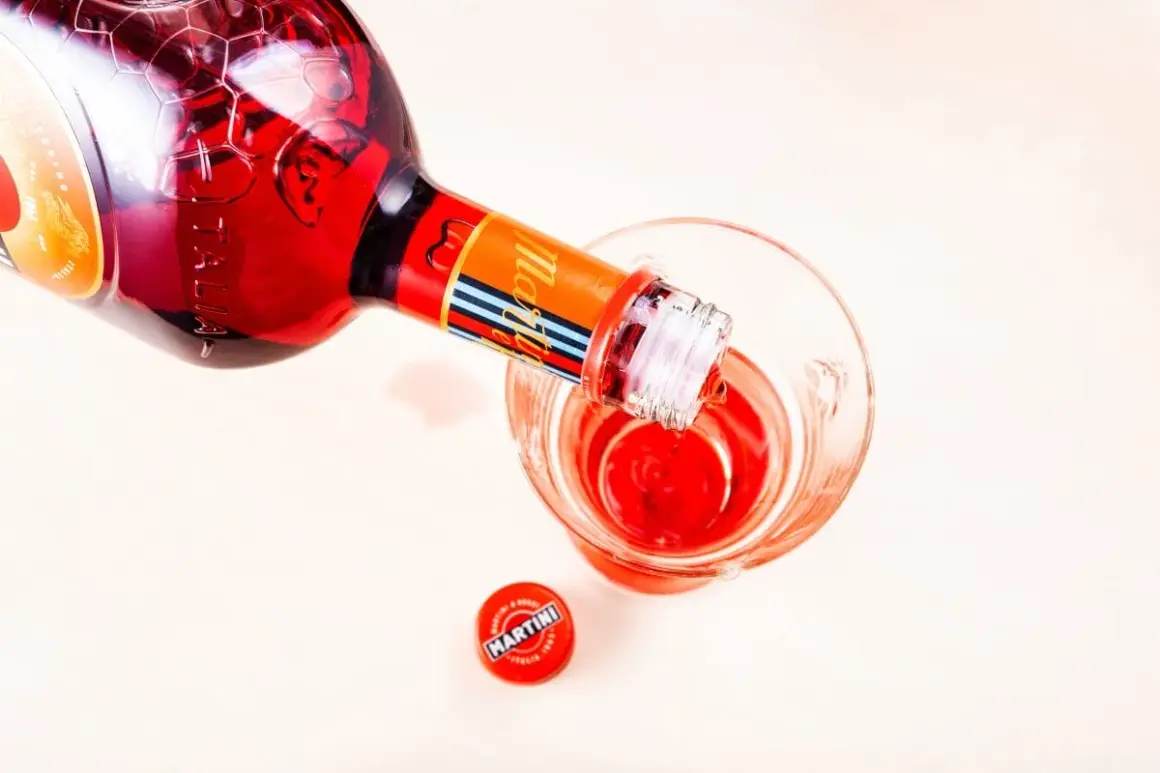 Czerwony Martini Fiero Prosecco nalewany do kieliszka. Obok leży zakrętka.