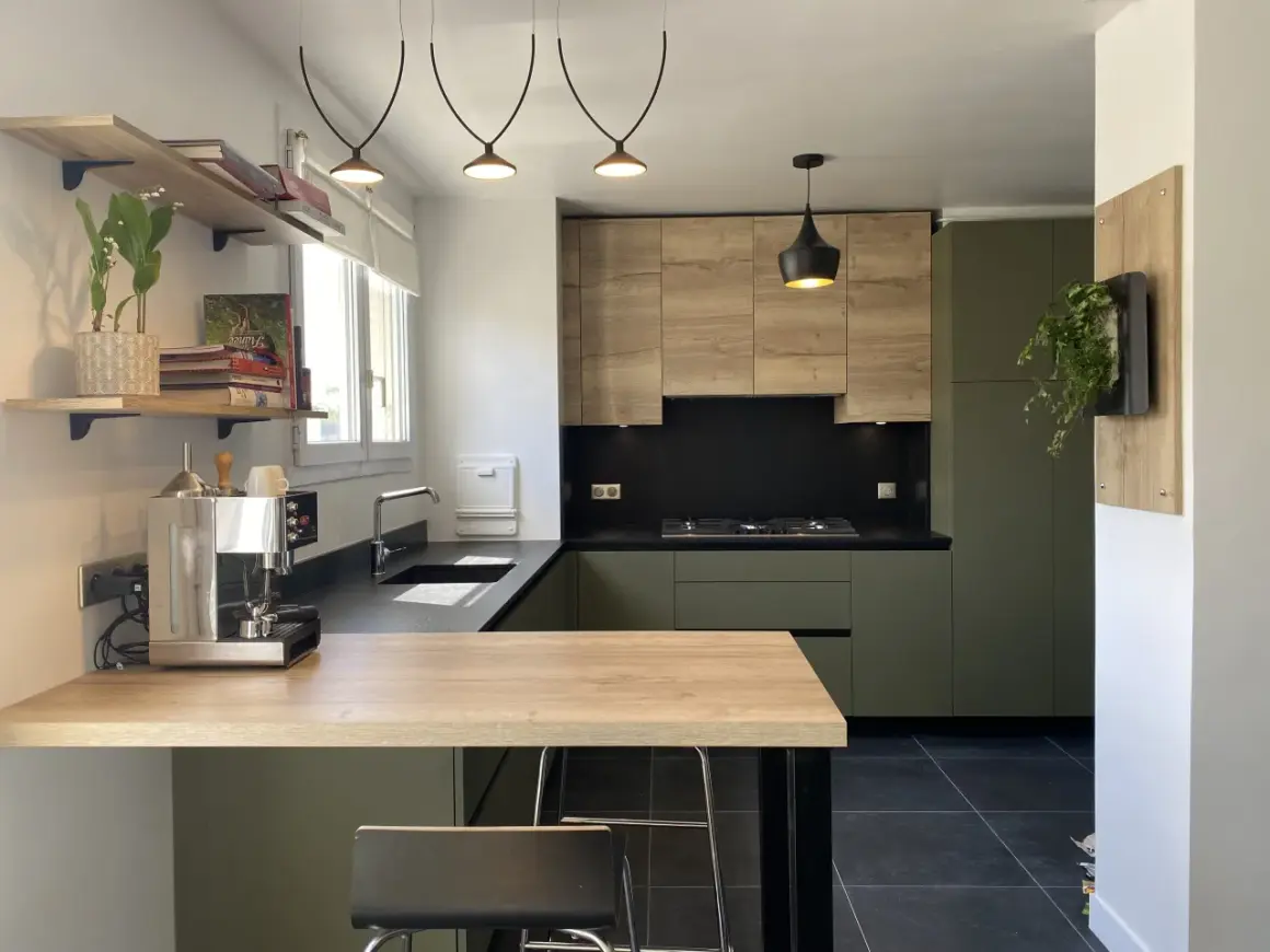 Cuisine moderne avec meubles verts et bois, plan de travail noir et îlot en bois.