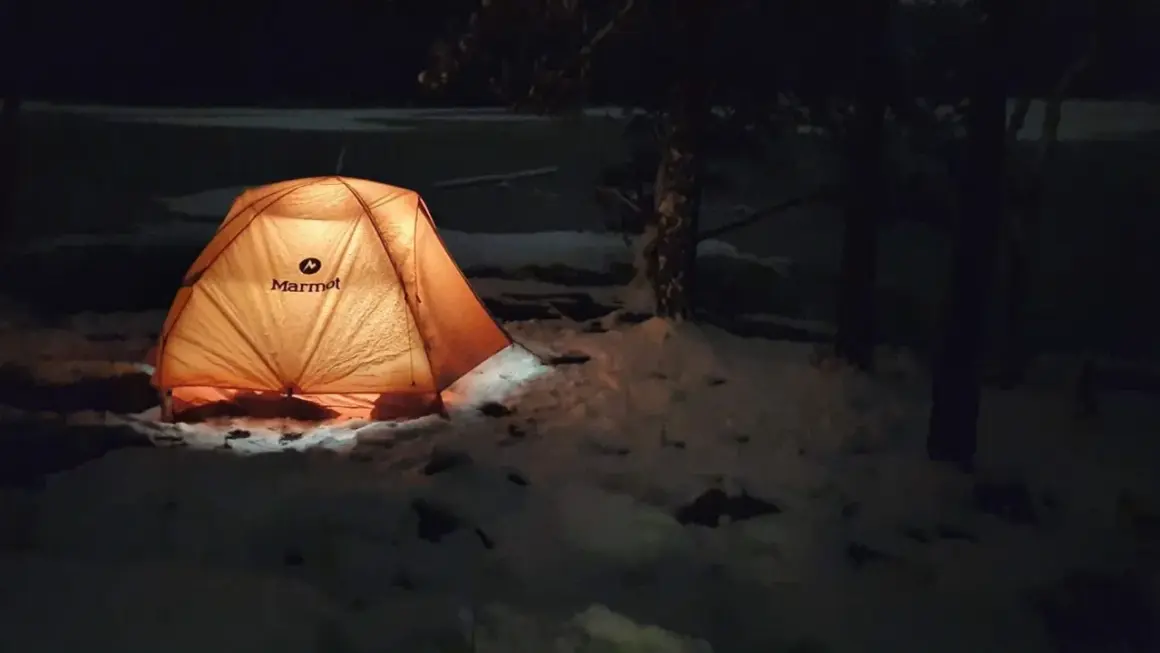 Upplyst tält i snön, redo för att sova ute på vintern.
