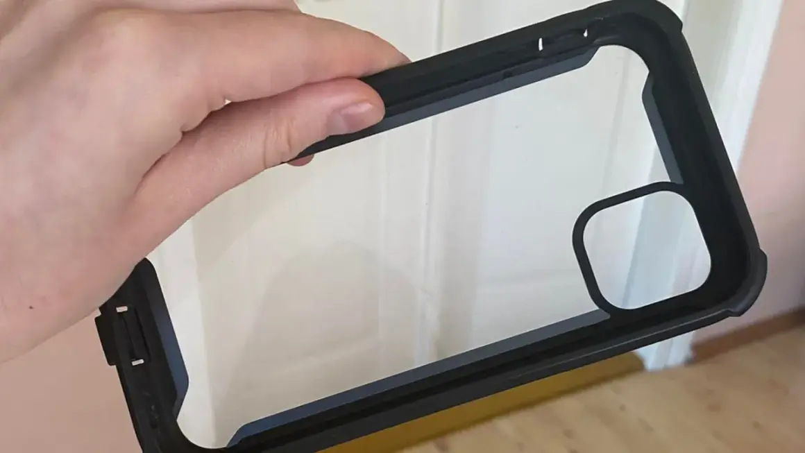 Dłoń trzyma czarne etui na telefon z przezroczystym tyłem. Dowiedz się, jak wyczyścić etui na telefon, aby wyglądało jak nowe.