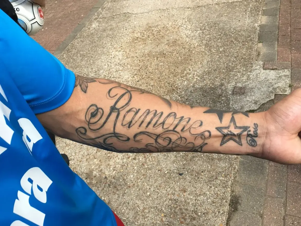 Damski tatuaż na przedramieniu z napisem "Ramone" i gwiazdką.