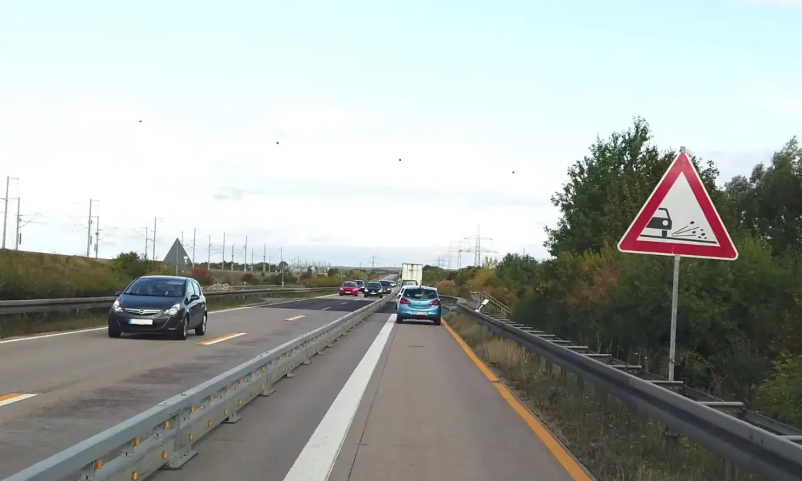 Achtung, stau schild warnt vor schleudernder Fahrbahn. Autos fahren auf der Autobahn.