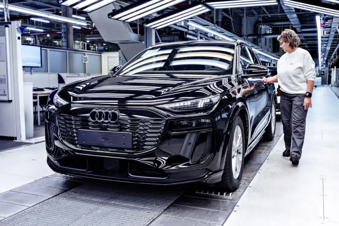Czarny Audi na linii produkcyjnej. Pracownica sprawdza jakość pojazdu, który opuszcza fabrykę w Niemczech.
