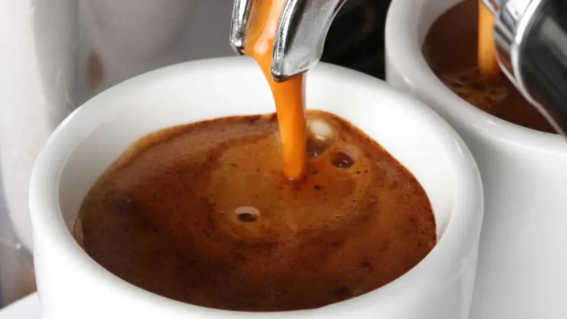 Caffè espresso che scende lentamente nella tazzina, creando una crema densa e invitante. Un piacere per gli occhi, se il caffè scende troppo piano, forse è ora di un caffè più forte.