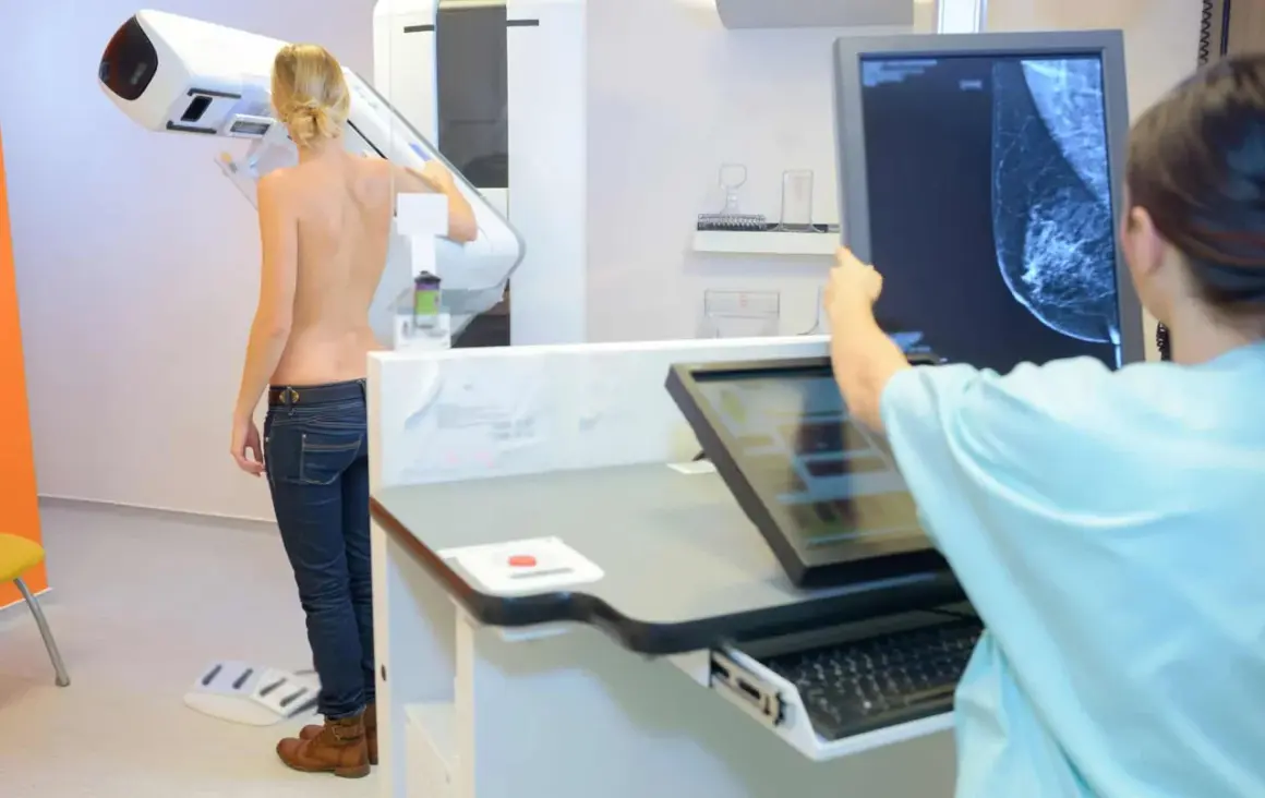 Frau wird mittels 3D Mammographie untersucht. Ärztin analysiert das Bild auf dem Monitor.