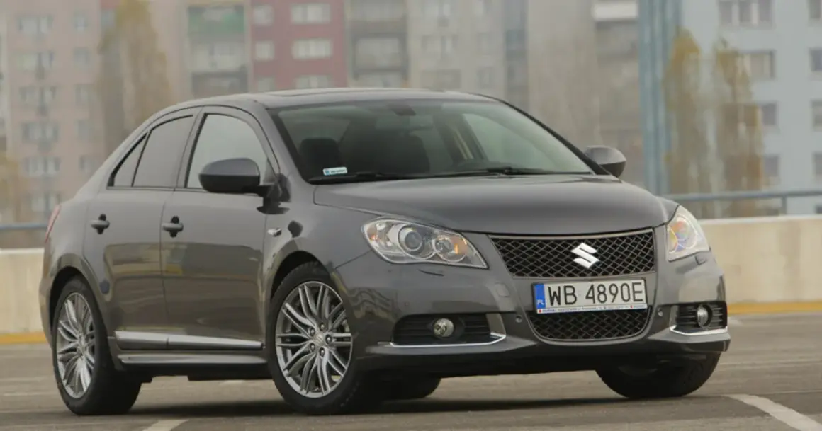 Szary Suzuki Kizashi z felgami i tablicą rejestracyjną WB 4890E na tle budynków.
