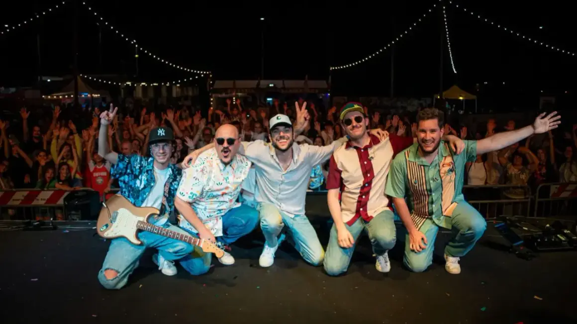 La tirock band festeggia con il pubblico, luci e chitarra elettrica sul palco.