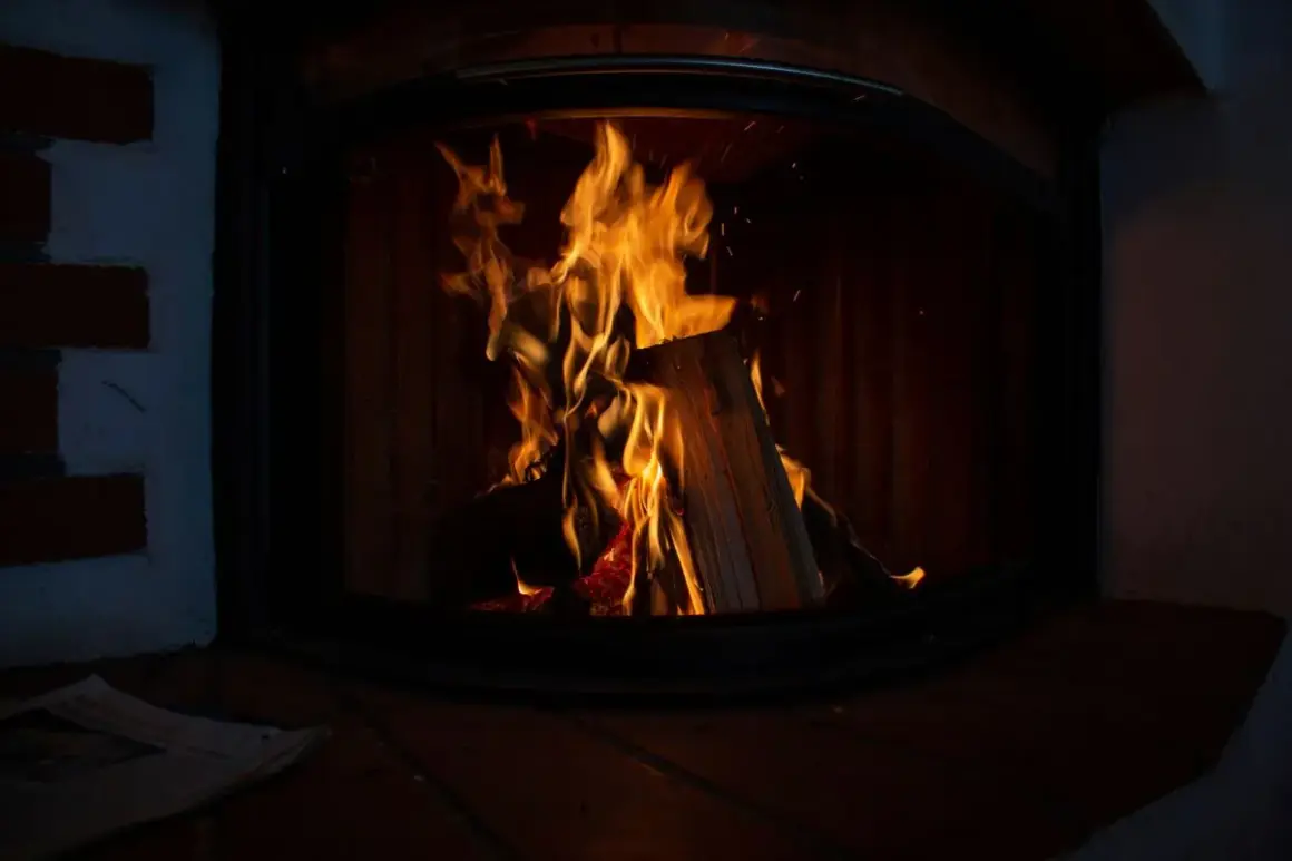 Flammen lodern im Kaminofen. Ein Zeitungsstapel liegt davor. Der Ofen ist nicht stillgelegt, es gibt Ausnahmen für gemütliche Abende.