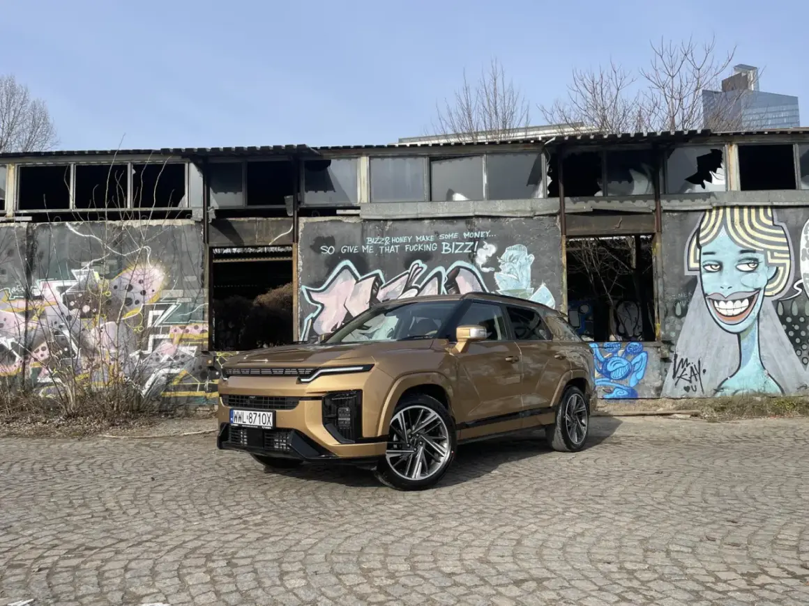 Złoty SsangYong Actyon na tle zniszczonego budynku z graffiti.