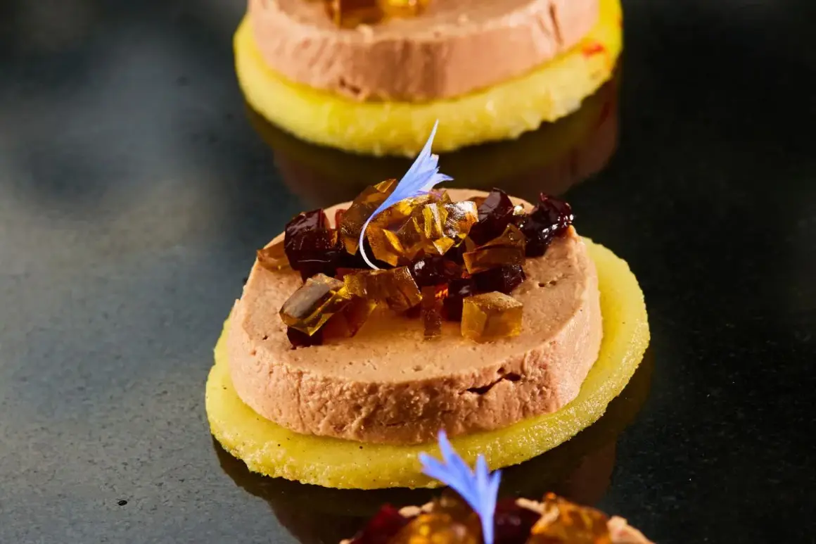 Délicieuse terrine de foie gras sur une tranche d'ananas, garnie de dés de gelée et d'une fleur bleue. Un vrai régal pour savoir comment démouler une terrine de foie gras.
