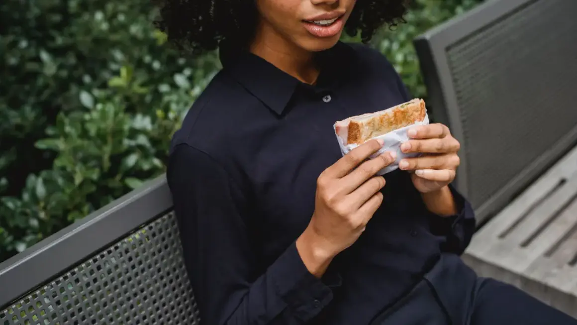 Frau hält Sandwich, wie bei der Sandwich-Methode für Feedback.