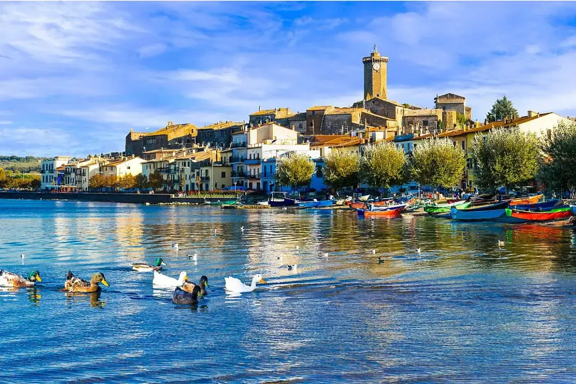 Anatre nuotano in un lago sereno, con un borgo pittoresco e barche colorate che si specchiano sull'acqua. Un'immagine da cartolina dei laghi italiani.