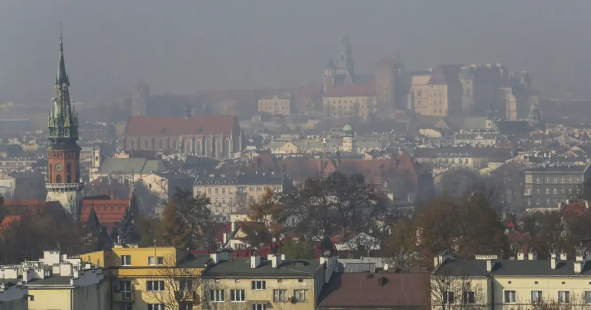 Mglisty widok Krakowa z wieżą kościelną i zamkiem. Warto wiedzieć, jak chronić się przed zanieczyszczeniami powietrza w takich warunkach.