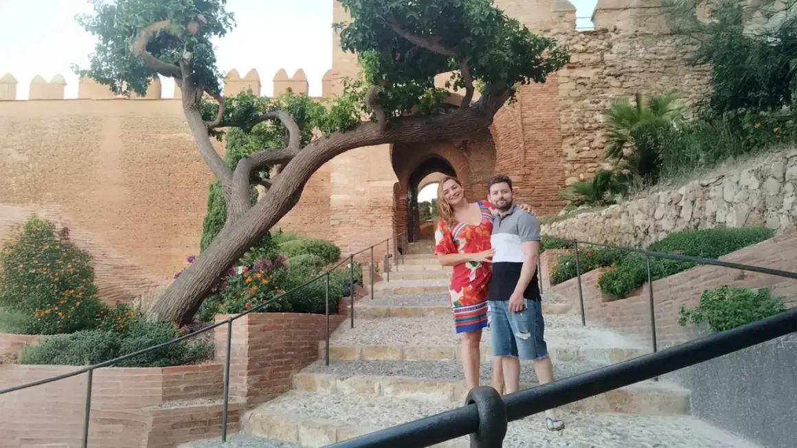 Pareja posando en escalinatas de piedra con un árbol retorcido y murallas de cañarete Almería de fondo.