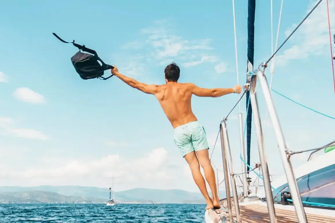 Uomo con zaino in barca a vela, un esempio di come vestirsi in barca a vela: costume e libertà.