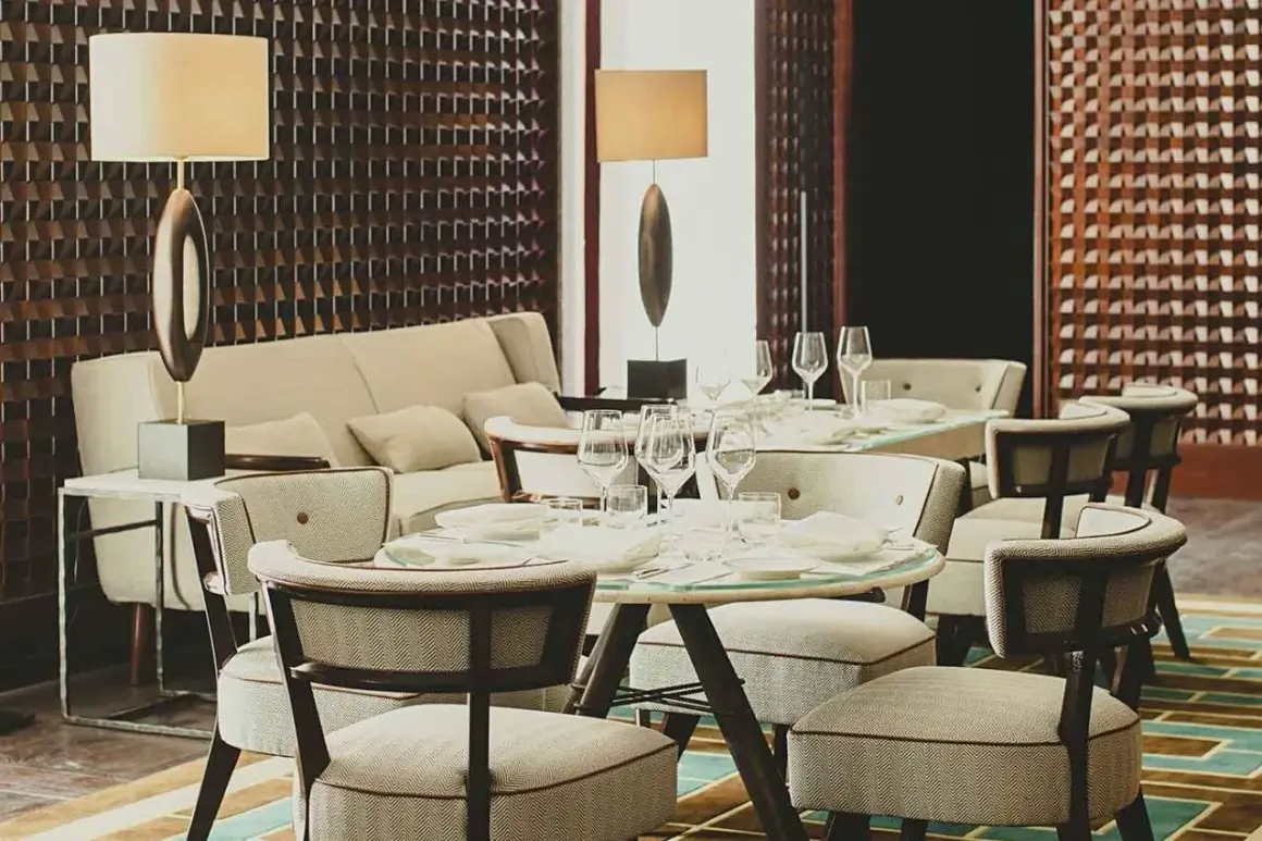 Eleganza in un ristorante di Milano: tavoli apparecchiati, divani accoglienti e luci soffuse creano un'atmosfera raffinata.