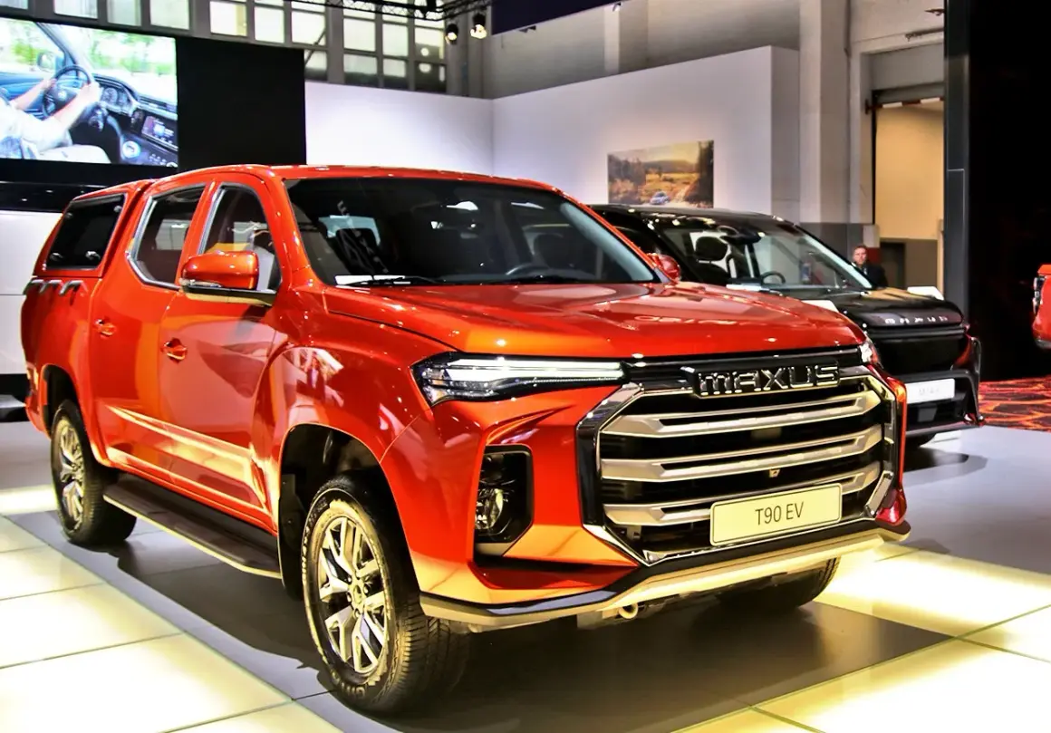Pomarańczowy Maxus T90 EV, chińska marka samochodów w Polsce, prezentuje się na wystawie.