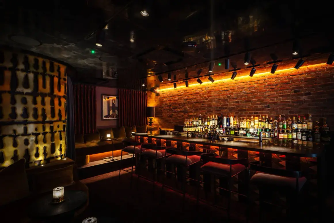 Interni di un bar londinese famosi, con mattoni a vista, illuminazione d'atmosfera e una vasta selezione di liquori dietro il bancone.