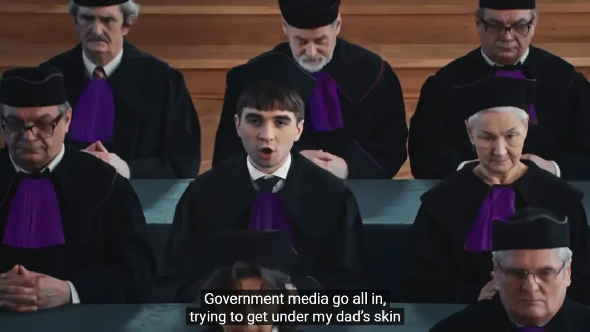 Młody mężczyzna w todze sądowej przemawia przed grupą sędziów w togach.