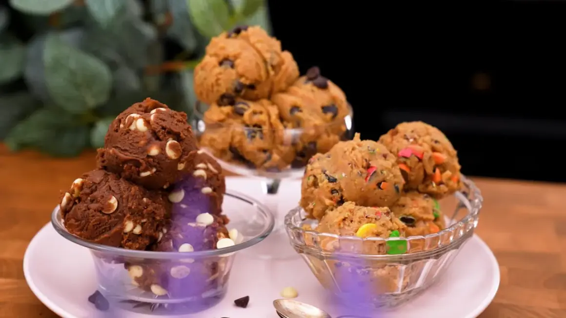 Tre skålar med olika sorters cookie dough recept: choklad med vita chokladknappar, klassisk med chokladknappar och en med färgglada godisbitar.
