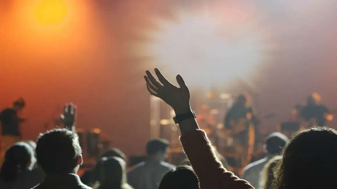 Menschen mit erhobenen Händen in einem Gottesdienst. Sie sind Teil der Pfingstbewegung, die sich durch lebendige Anbetung auszeichnet.
