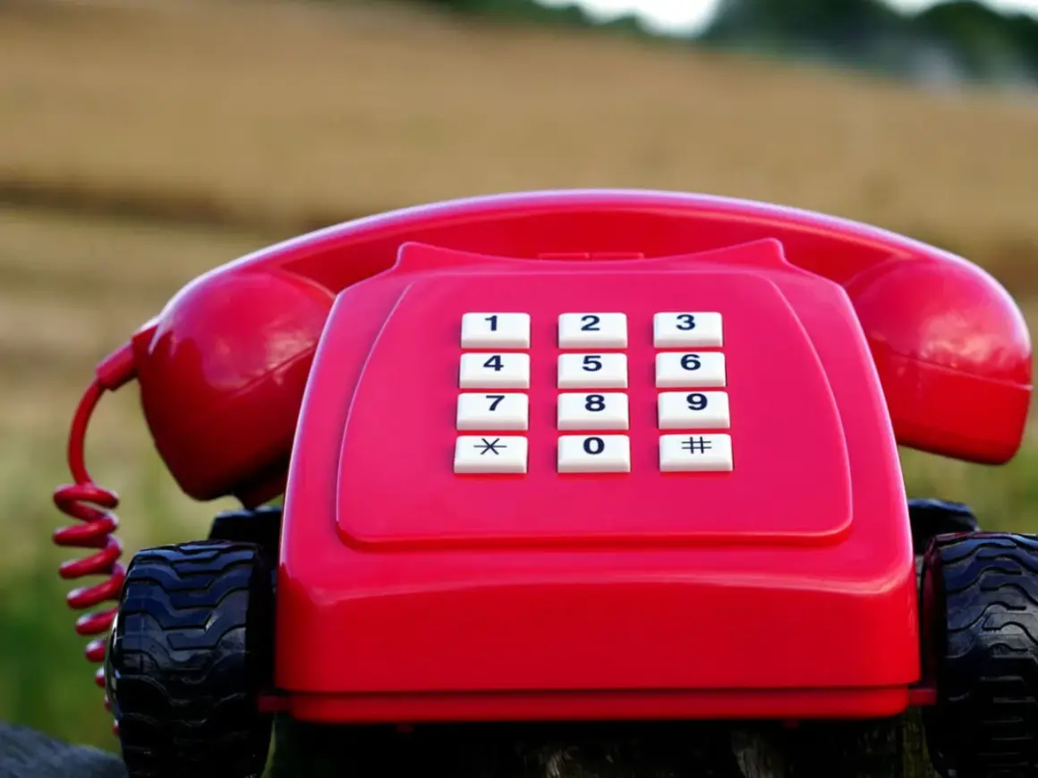 Czerwony telefon stacjonarny na kółkach, jakby gotowy do podróży po najtańszy abonament.