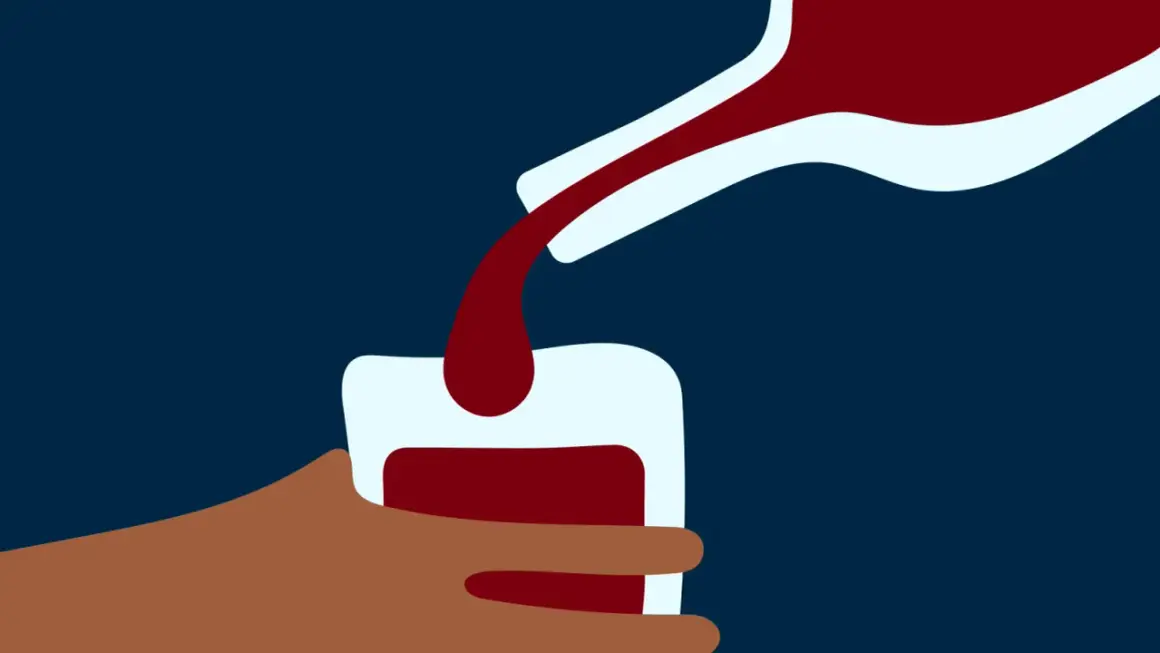 En hand håller ett glas medan mörkt vin hälls upp. En bild som kan symbolisera alkoholist beteende.