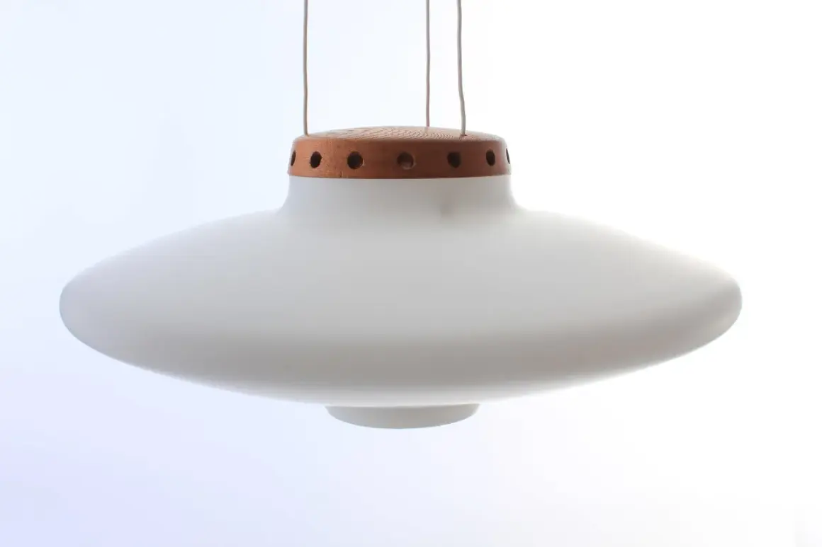 En vit, svävande ufo lampa med en trädetalj upptill.