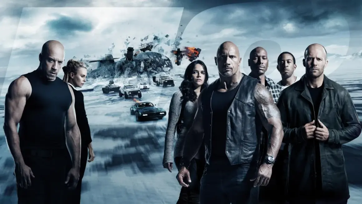 Die Hauptdarsteller der besetzung von Fast & Furious 8 stehen vor einer eisigen Landschaft mit explodierenden Fahrzeugen und einem Helikopter.