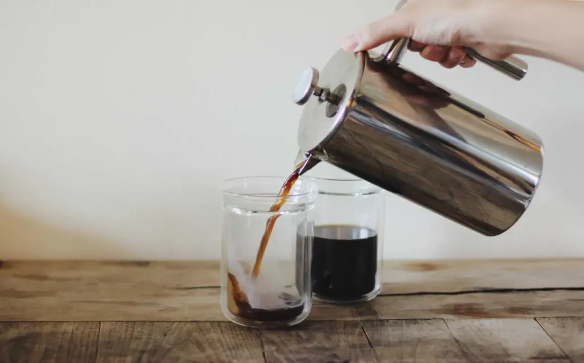 Versando caffè americano da una french press in due bicchieri. Le dosi caffè americano sono perfette per iniziare la giornata.
