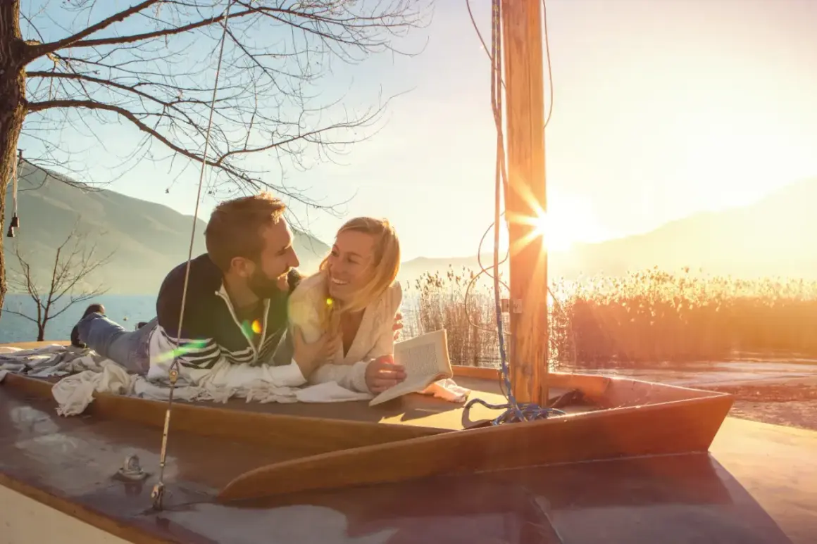 Glückliches Paar auf einem Boot bei Sonnenuntergang. Ihre christliche Partnersuche Erfahrungen haben sie hierher geführt.