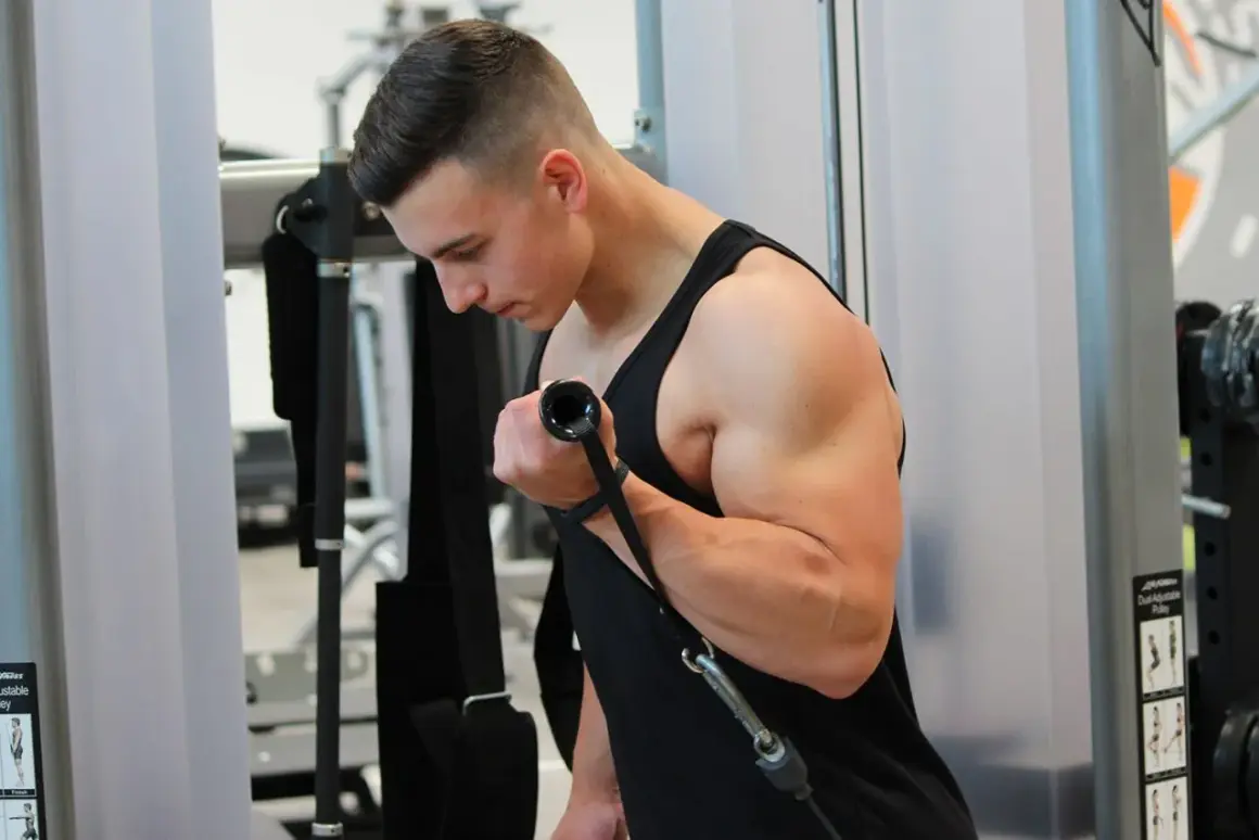 Ein Mann trainiert im Fitnessstudio und baut beeindruckende Muskeln am Oberarm auf.