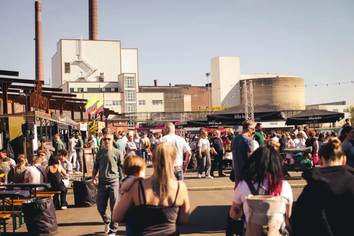 Menschen genießen das Street Food Festival Bergisch Gladbach mit vielen Essensständen und bunter Atmosphäre vor Industriebauten.