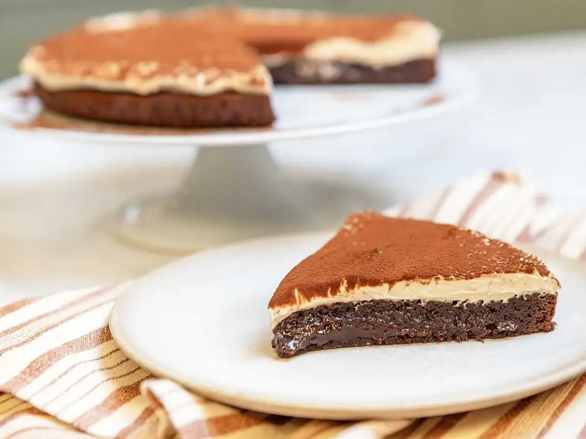 En saftig kladdkaka med en krämig topping, pudrad med kakao. Perfekt för fikat!