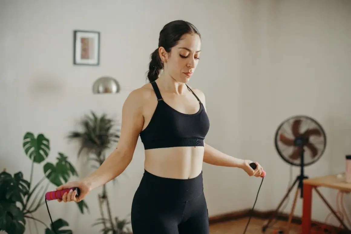 Femme en tenue de sport s'entraînant avec une corde à sauter, renforçant son périnée.
