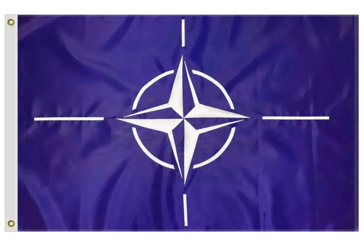 Flaga NATO: granatowe tło, biała czteroramienna gwiazda z okręgiem i czterema białymi liniami.