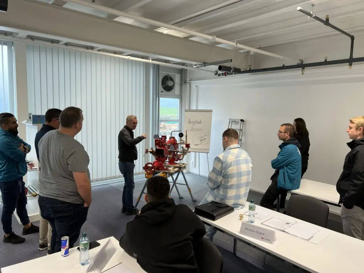 Männer nehmen an einer Schulung teil, bei der ein Sprinklerwart die Funktionsweise eines Sprinklersystems erklärt.