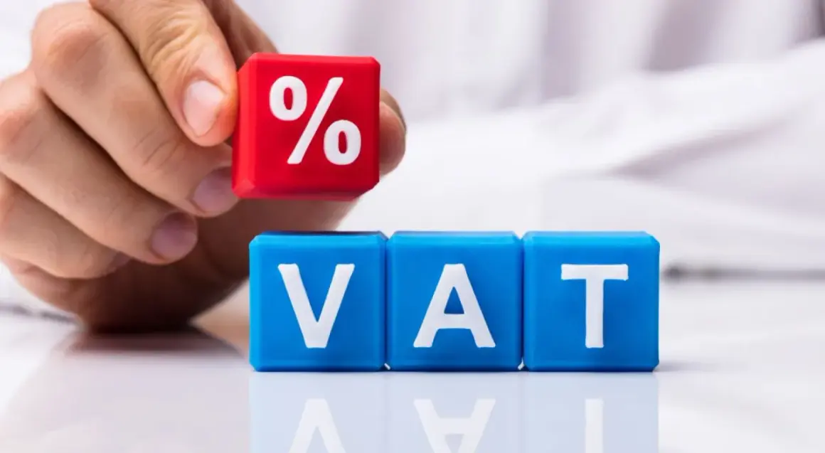 Dłoń układa kostkę z symbolem procentu na kostkach z literami VAT. Rozważasz usługę gastronomiczną a VAT?