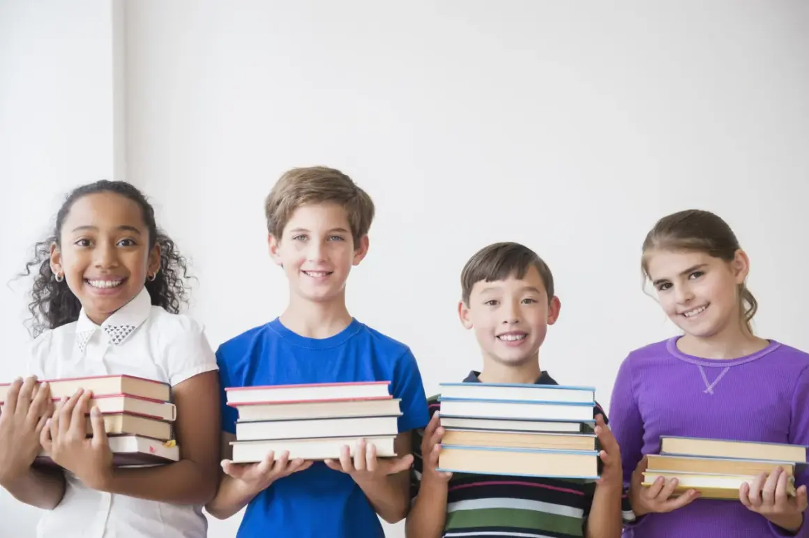 Vier lächelnde Kinder der 3. Klasse präsentieren stolz ihre Bücher für die buchvorstellung klasse 3.