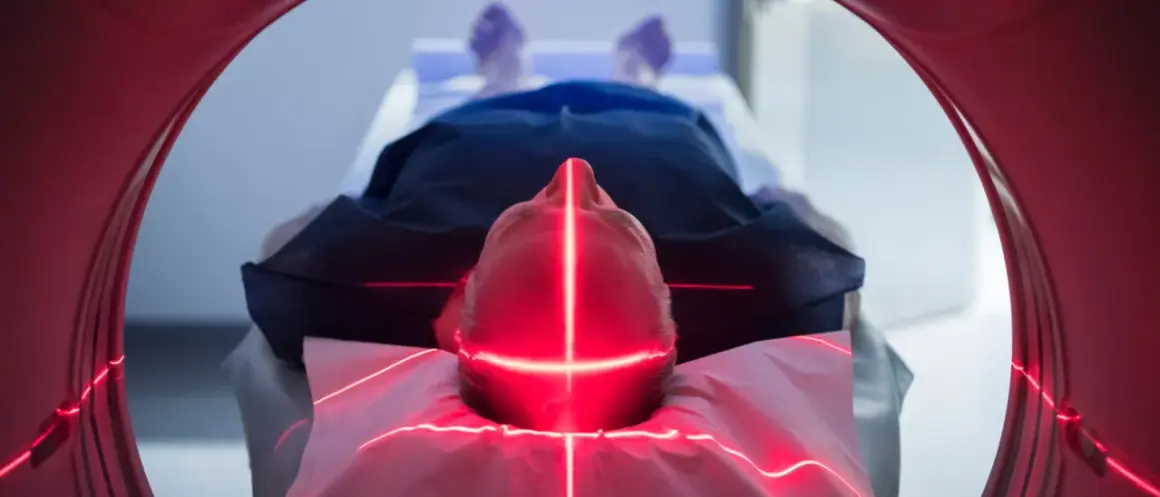 Mann liegt unter roten Laserlinien, die auf seinen Kopf zielen. Dies ist Teil einer neuen Krebstherapie.